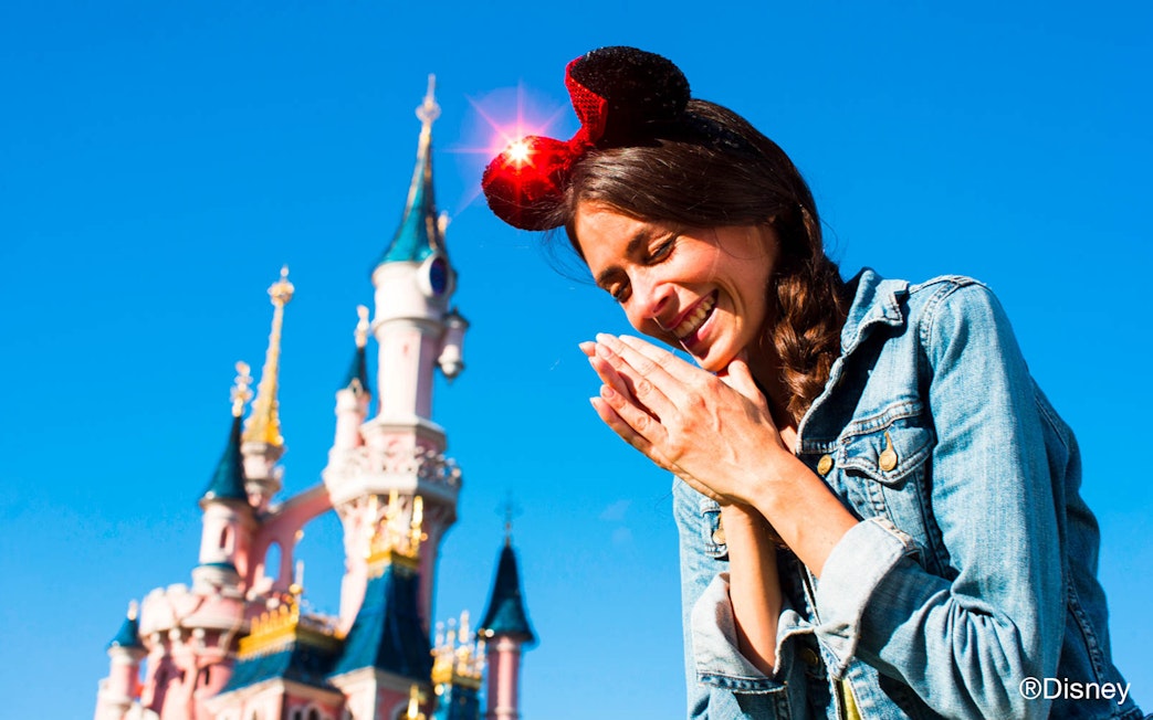 Visitor enjoying Disneyland Paris with Sleeping Beauty Castle in the background.