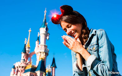 Visitor enjoying Disneyland Paris with Sleeping Beauty Castle in the background.
