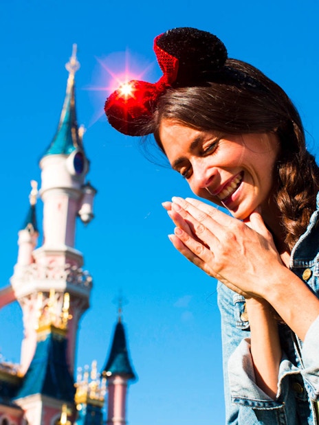 Visitor enjoying Disneyland Paris with Sleeping Beauty Castle in the background.