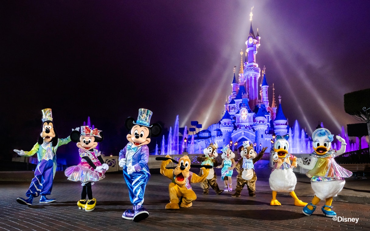 Disney characters in front of Sleeping Beauty Castle at Disneyland Paris.