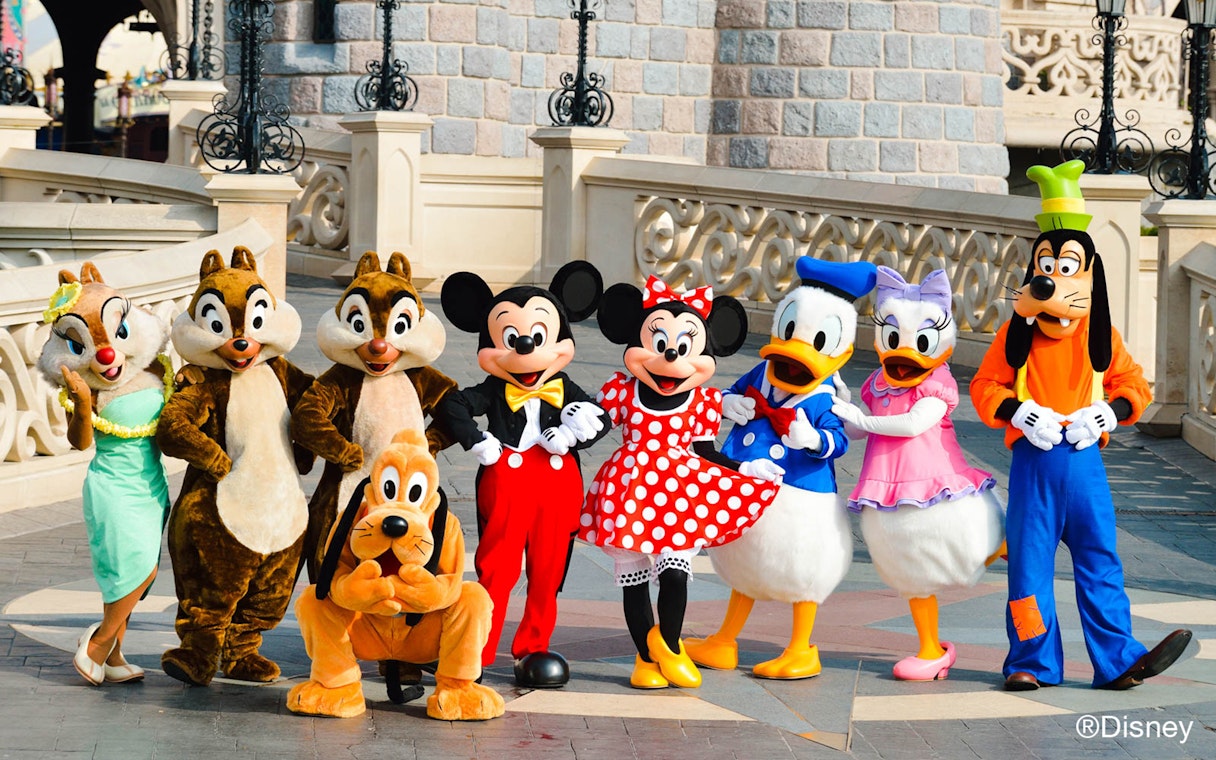 Disney characters posing in front of Sleeping Beauty Castle at Disneyland Paris.