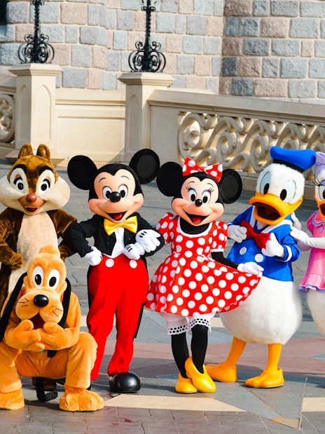 Disney characters posing in front of Sleeping Beauty Castle at Disneyland Paris.
