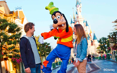 Goofy entertaining guests at Disneyland Paris with Sleeping Beauty Castle in the background.