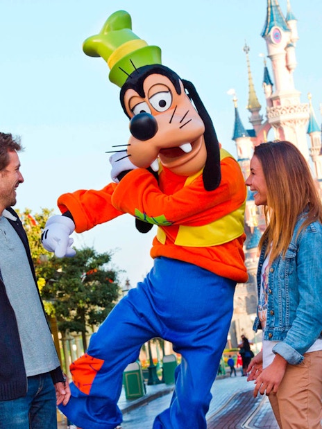 Goofy entertaining guests at Disneyland Paris with Sleeping Beauty Castle in the background.