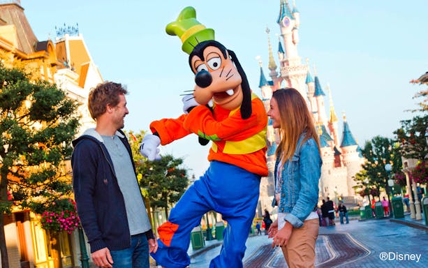 Goofy entertaining guests at Disneyland Paris with Sleeping Beauty Castle in the background.