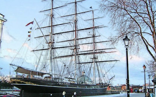 Cutty Sark ship docked in Greenwich, London, with visitors walking nearby.