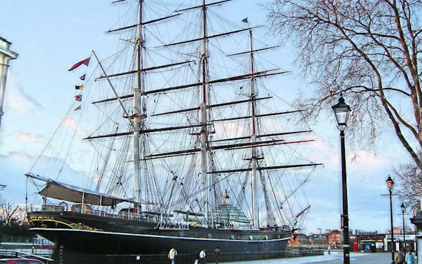 Cutty Sark ship docked in Greenwich, London, with visitors walking nearby.