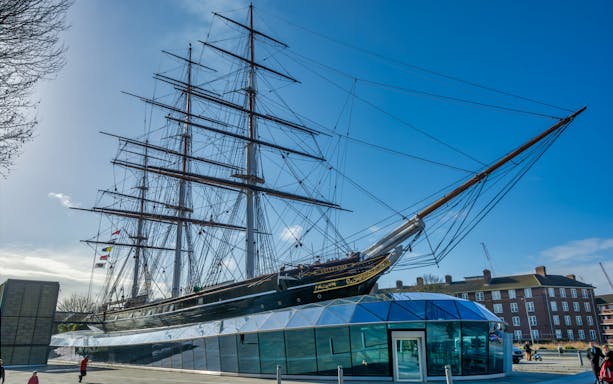 Cutty Sark ship in Greenwich, London, with modern glass entrance below.