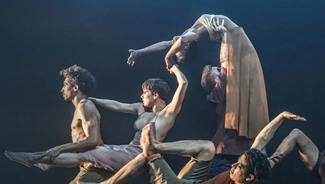 Dancers performing an intricate lift in "Message In A Bottle" show.