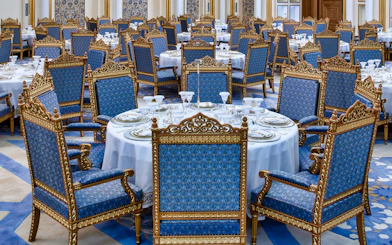 Elegant dining setup at Qasr Al Watan, Abu Dhabi, with ornate blue and gold chairs.