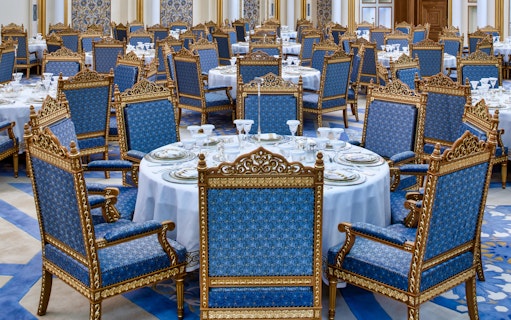 Elegant dining setup at Qasr Al Watan, Abu Dhabi, with ornate blue and gold chairs.