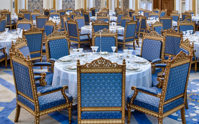 Elegant dining setup at Qasr Al Watan, Abu Dhabi, with ornate blue and gold chairs.