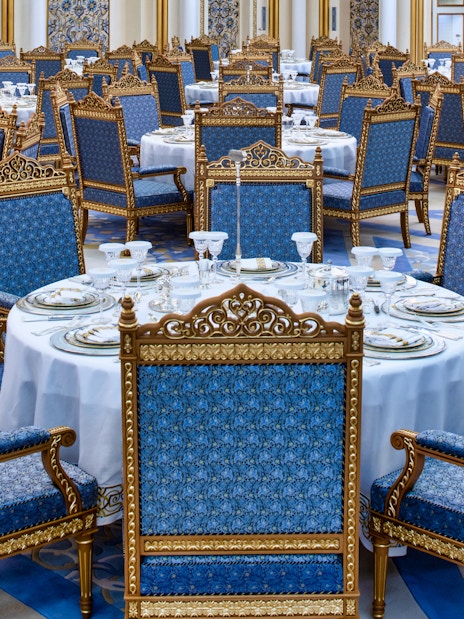 Elegant dining setup at Qasr Al Watan, Abu Dhabi, with ornate blue and gold chairs.