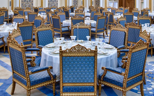 Elegant dining setup at Qasr Al Watan, Abu Dhabi, with ornate blue and gold chairs.