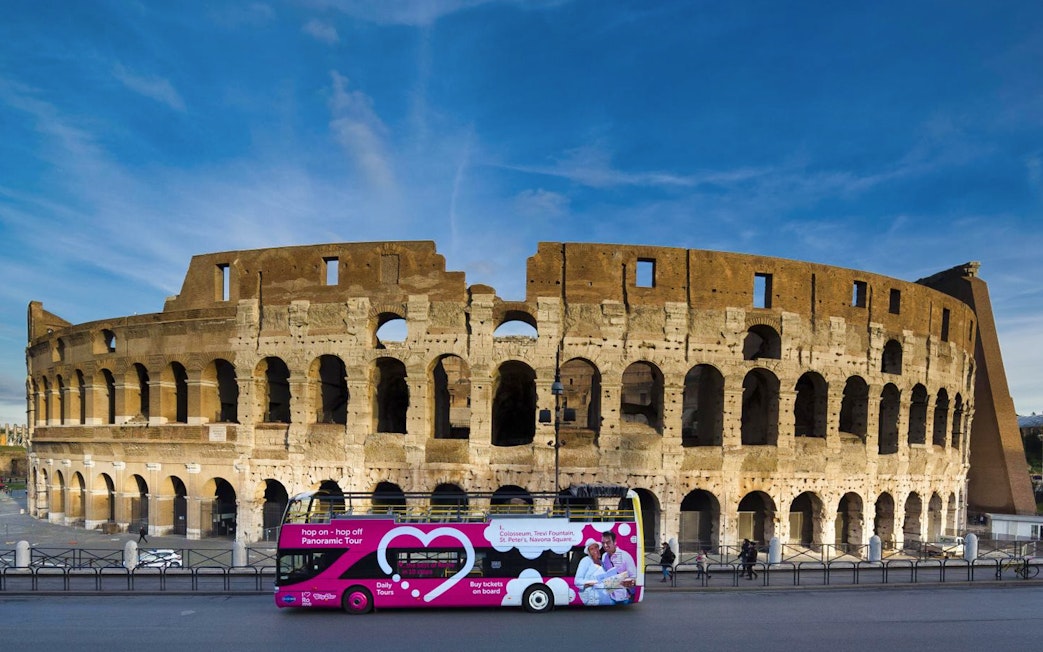 Hop-on hop-off tour bus in front of the Colosseum, Rome.