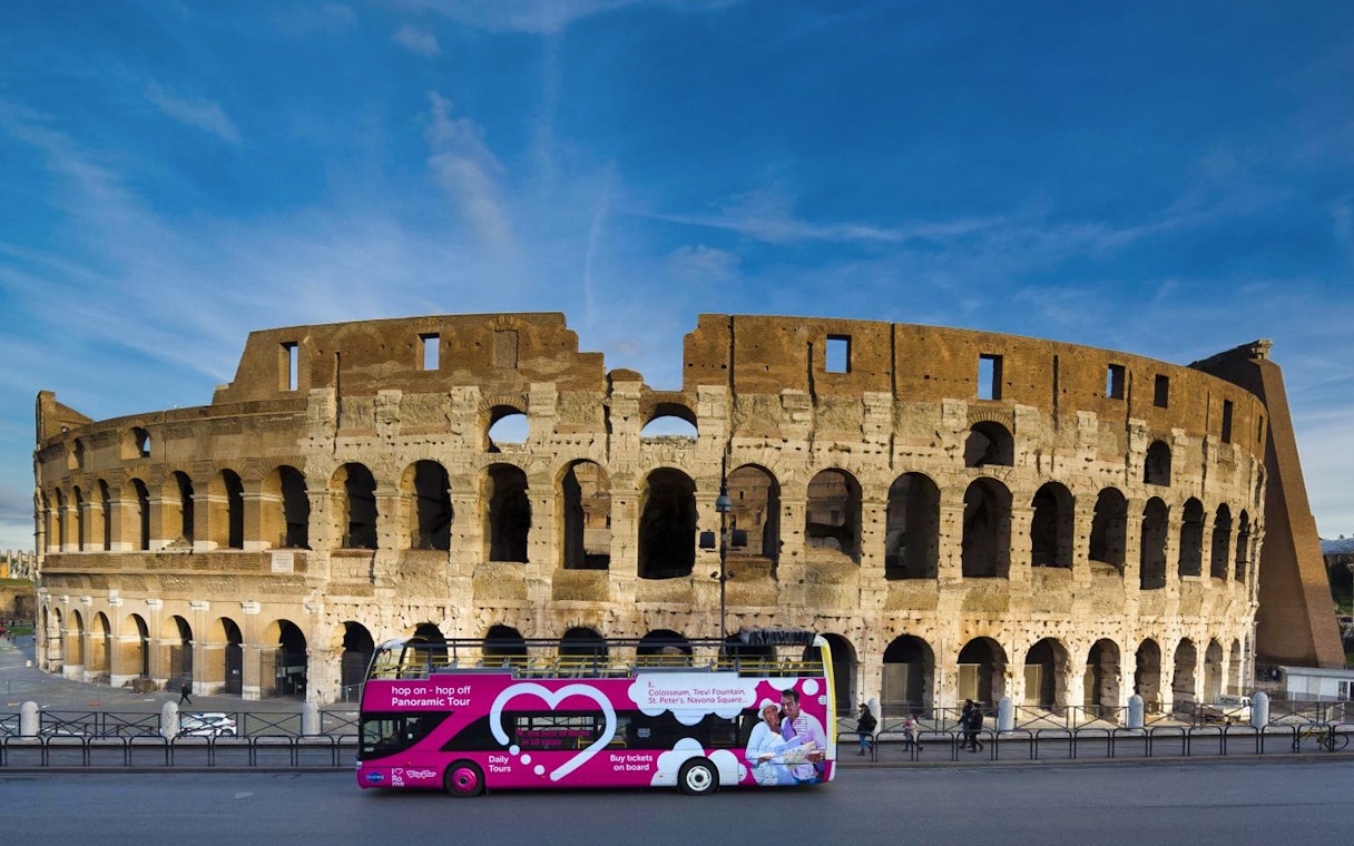 Hop-on hop-off tour bus in front of the Colosseum, Rome.