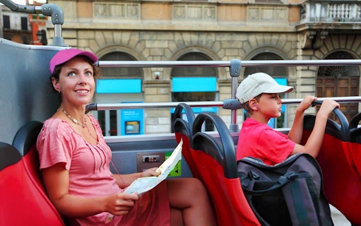 Tourists on Rome hop-on hop-off bus with map, exploring city landmarks.