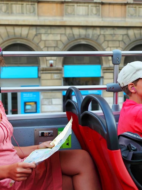 Tourists on Rome hop-on hop-off bus with map, exploring city landmarks.