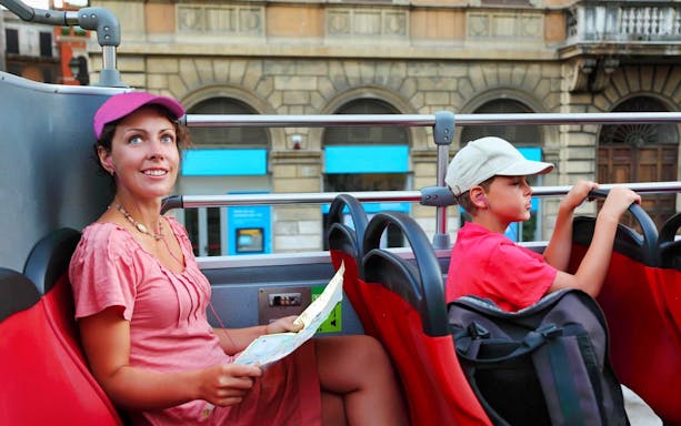 Tourists on Rome hop-on hop-off bus with map, exploring city landmarks.