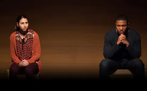Two people sitting on stage during a performance of "Actually.