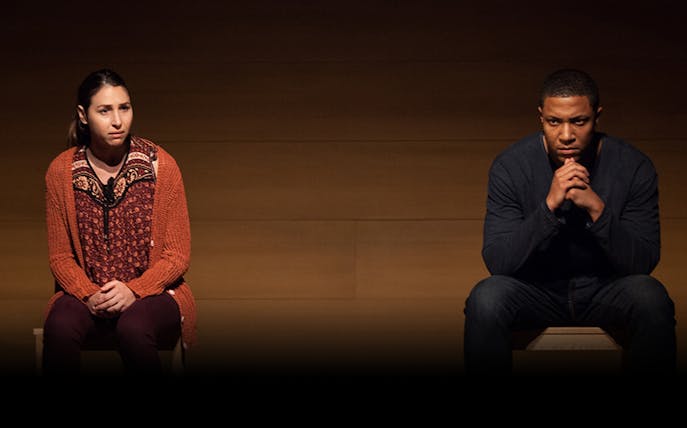 Two people sitting on stage during a performance of "Actually.