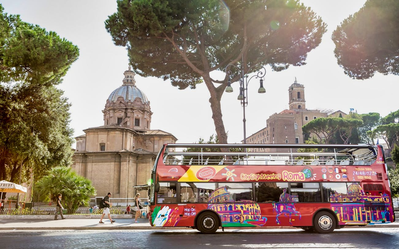 Red double-decker tour bus in front of a historic building in Rome, Italy.