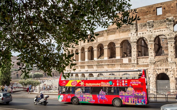Red hop-on hop-off tour bus in front of the Colosseum in Rome.