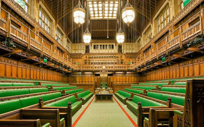 UK Parliament House of Commons chamber, green benches, guided tour setting.