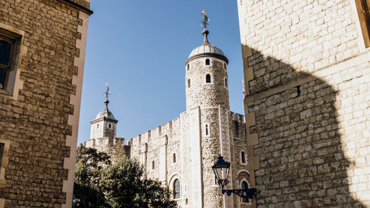 Tower of London stone walls and turrets under clear sky.