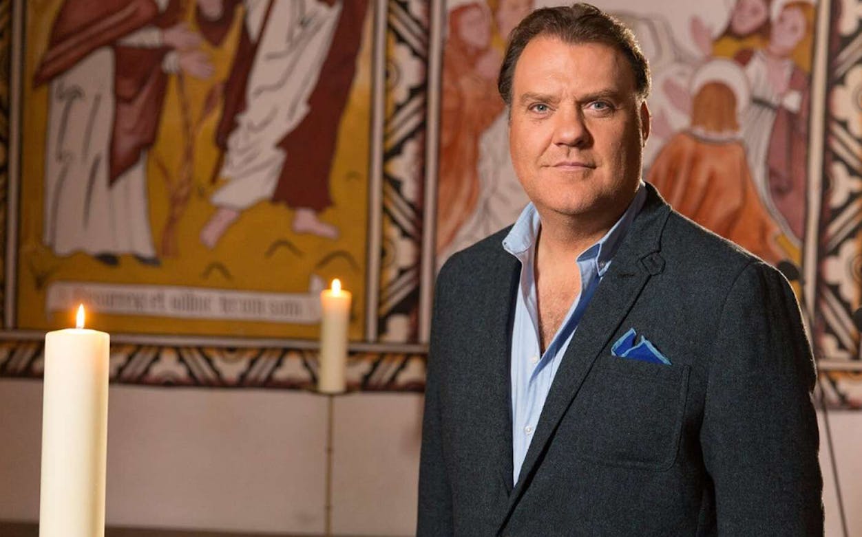 Opera singer in front of a mural with lit candles, Bryn Terfel in Concert.