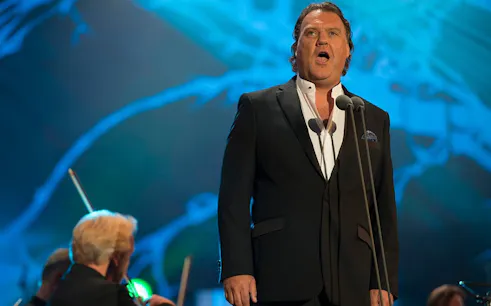 Opera singer performing on stage with orchestra in background