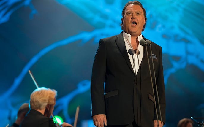 Opera singer performing on stage with orchestra in background