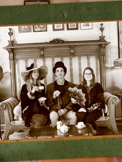 Visitors in vintage attire enjoying tea at Casa Batlló, Barcelona, with period decor.