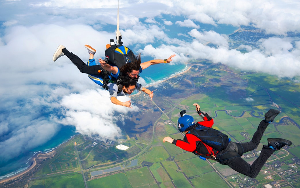 Skydivers tandem freefall over Great Ocean Road coastline, Australia.