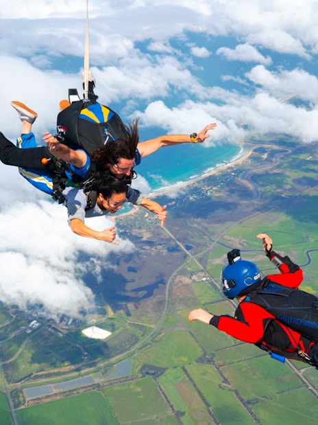 Skydivers tandem freefall over Great Ocean Road coastline, Australia.