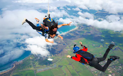 Skydivers tandem freefall over Great Ocean Road coastline, Australia.