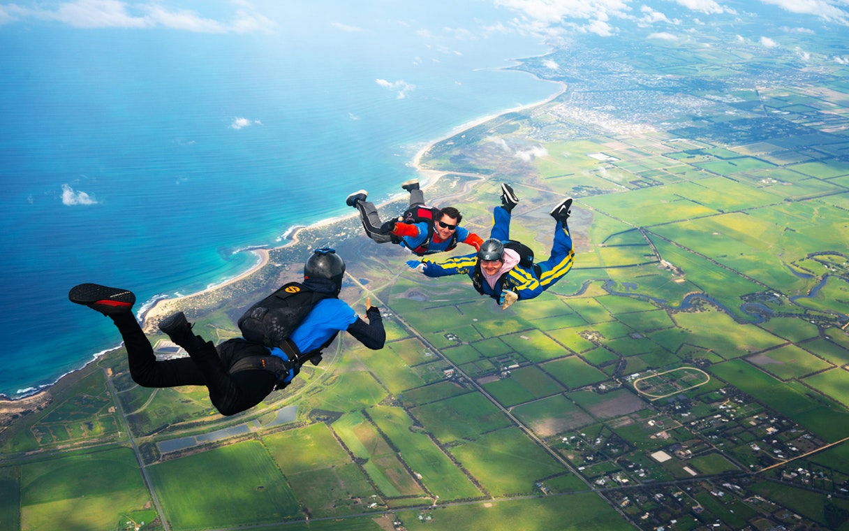 Skydivers tandem freefall over Great Ocean Road coastline, Australia.
