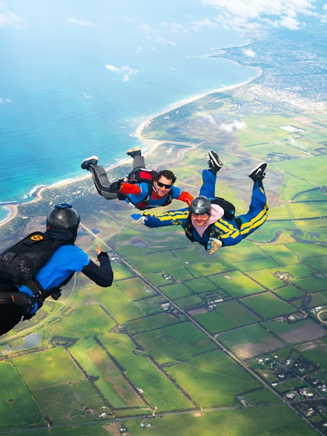 Skydivers tandem freefall over Great Ocean Road coastline, Australia.