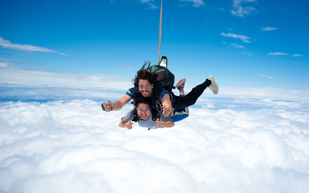 Tandem skydivers freefalling above clouds on Great Ocean Road.