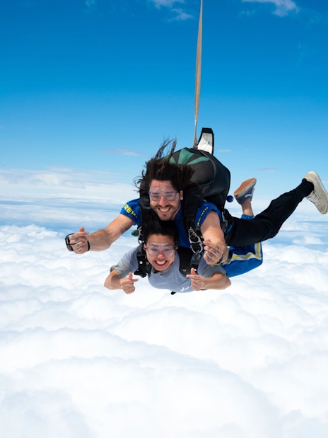 Tandem skydivers freefalling above clouds on Great Ocean Road.