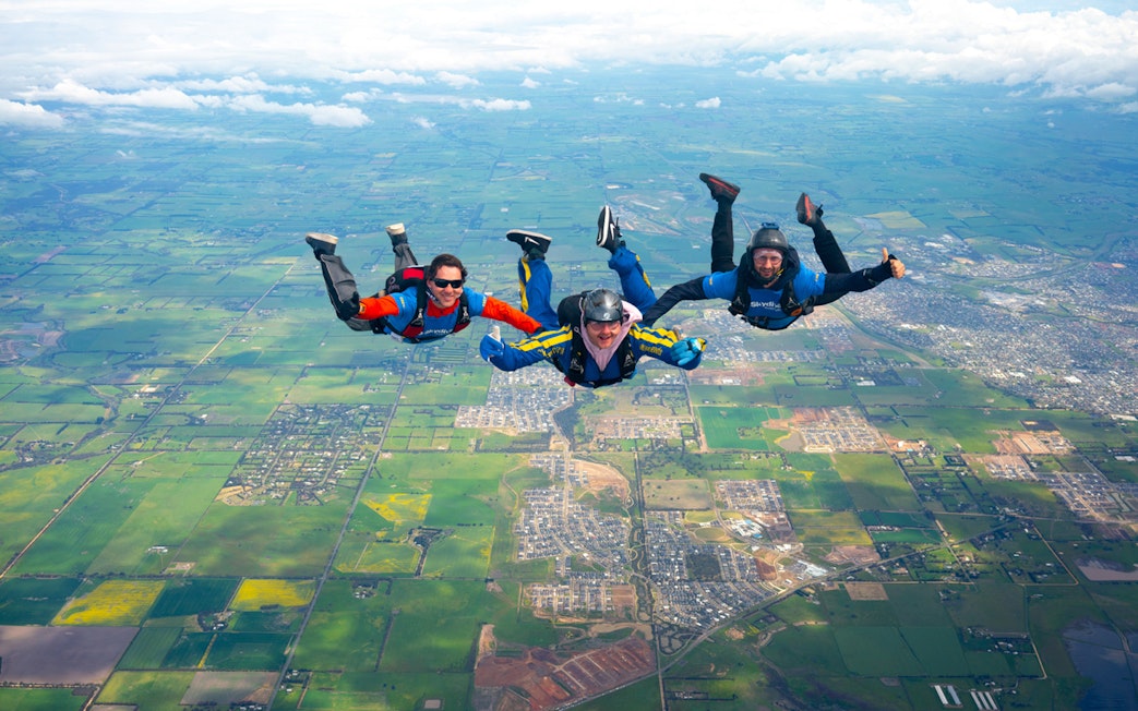 Skydivers in tandem freefall over Great Ocean Road, Australia.