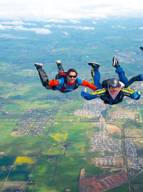 Skydivers in tandem freefall over Great Ocean Road, Australia.