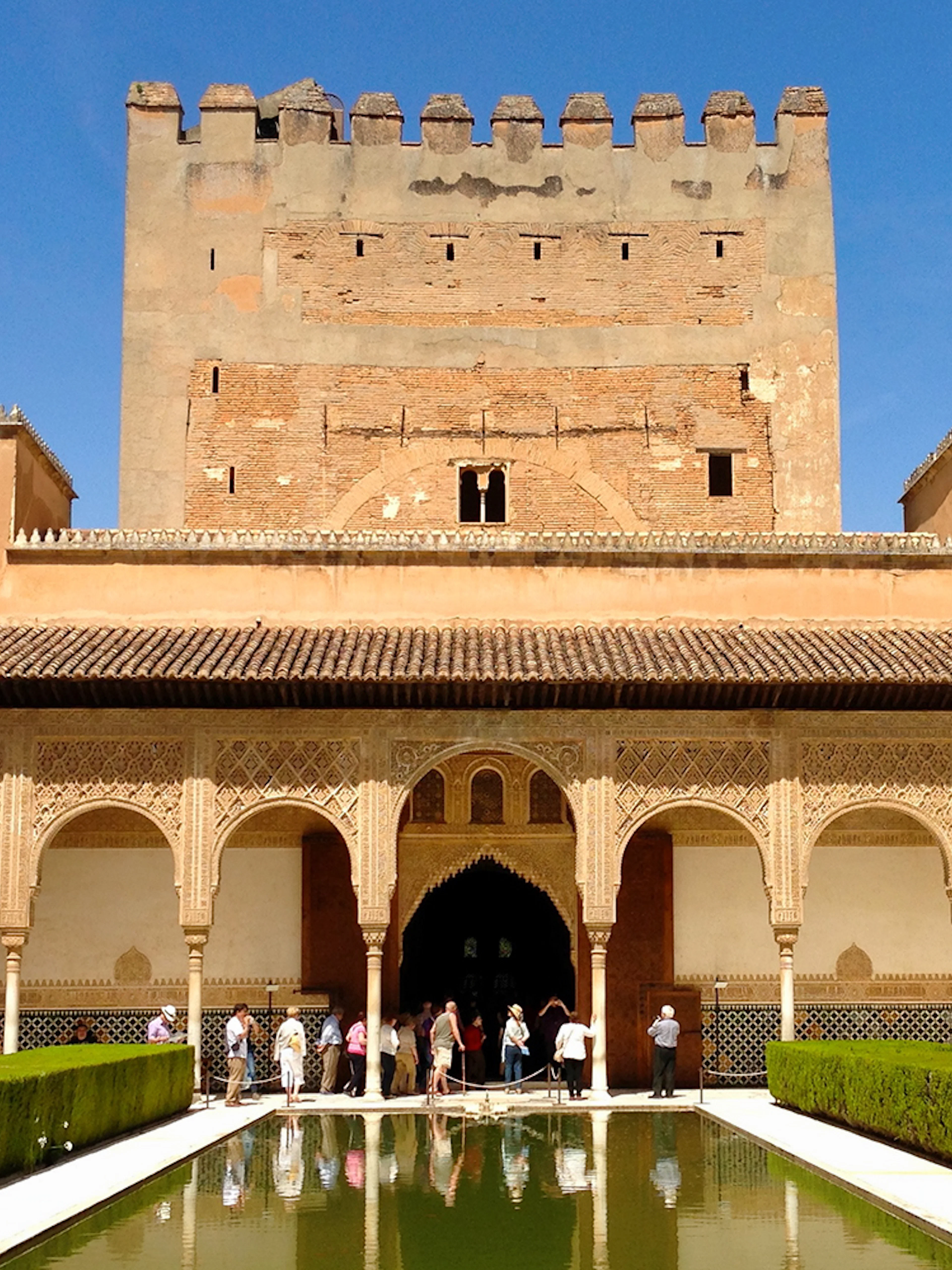 Alhambra's Patio de los Arrayanes with reflecting pool and visitors, Granada, Spain.