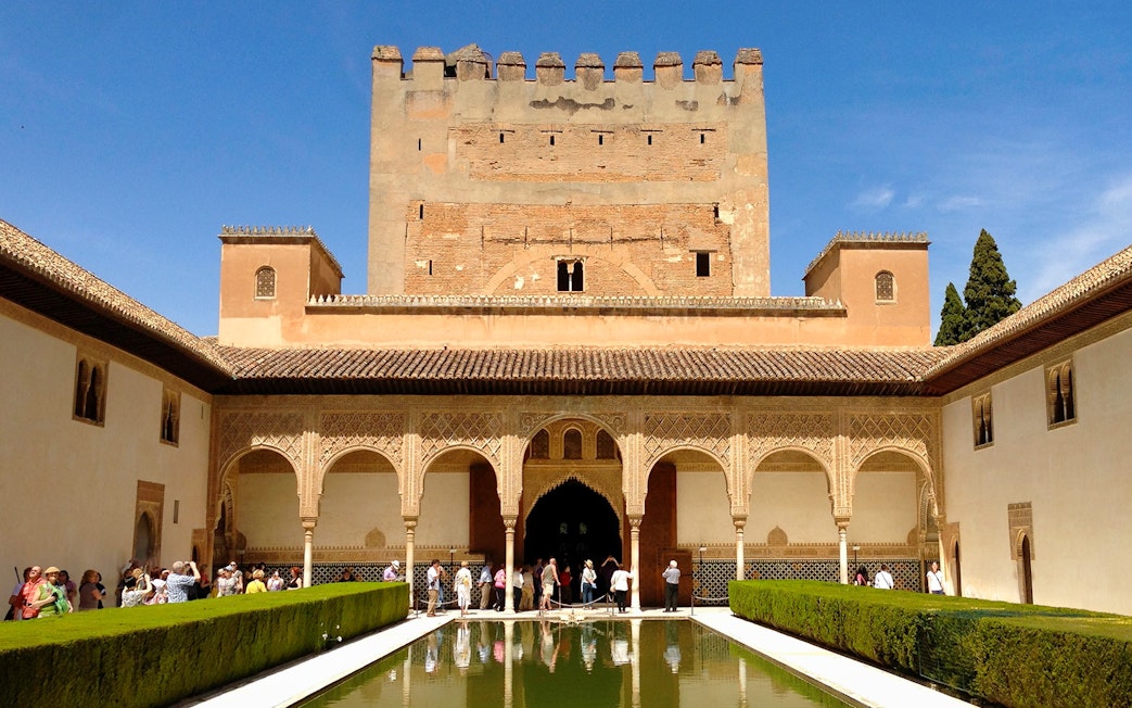 Alhambra's Patio de los Arrayanes with reflecting pool and visitors, Granada, Spain.