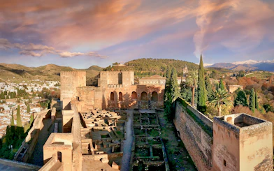 Alhambra fortress with scenic view of Granada, Spain, surrounded by hills and trees.