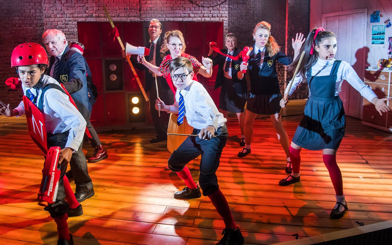 Children in school uniforms acting in a stage play of "The Secret Diary of Adrian Mole aged 13 3/4".