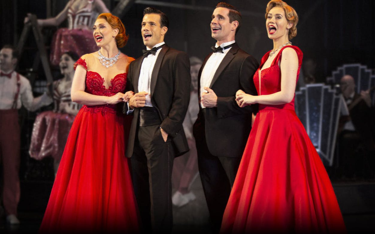 Performers in formal attire singing on stage during a "White Christmas" show.