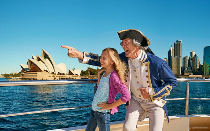 Captain and child on Sydney Harbour cruise with Opera House in view.