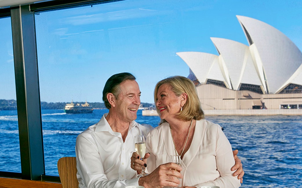 Couple enjoying champagne on a Sydney Harbour dinner cruise with Opera House view.