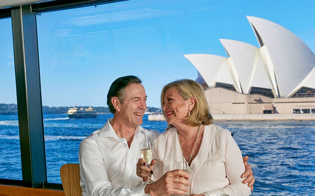 Couple enjoying champagne on a Sydney Harbour dinner cruise with Opera House view.